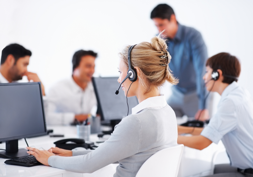 woman at screen with headphones and other workers