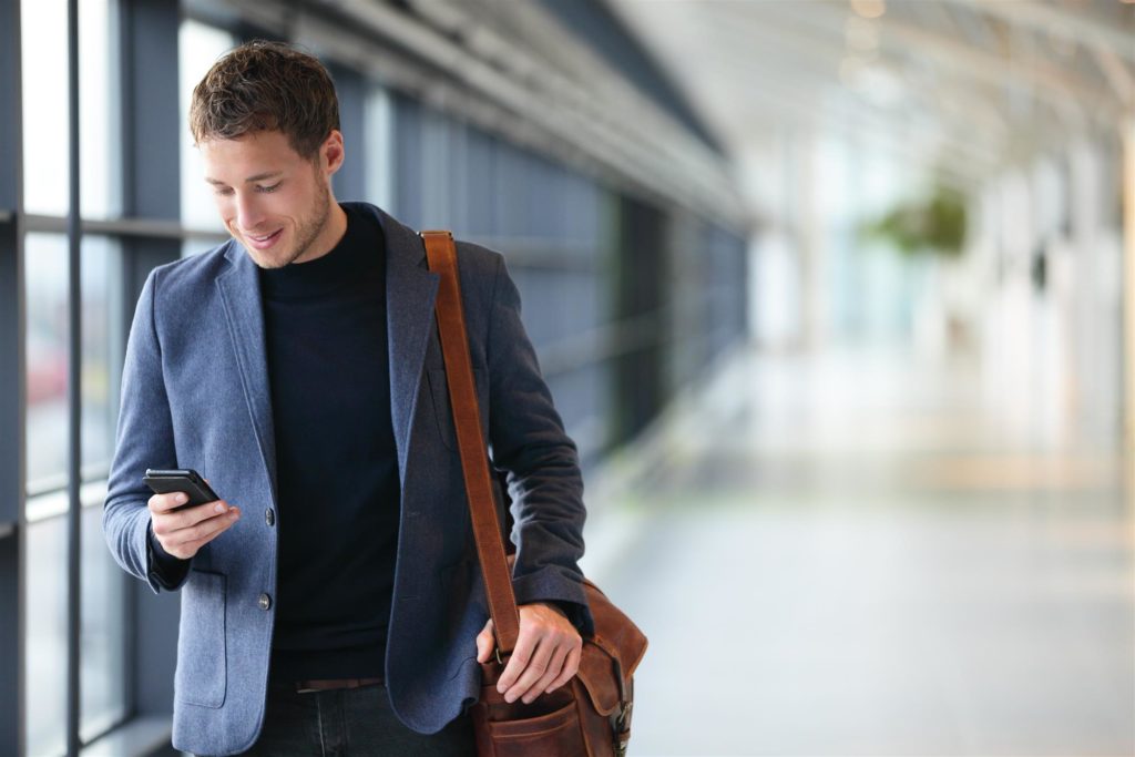 Young man using smartphone walking in airport