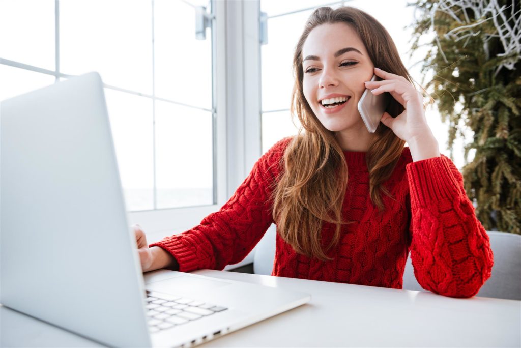 Woman using smartphone and looking at laptop