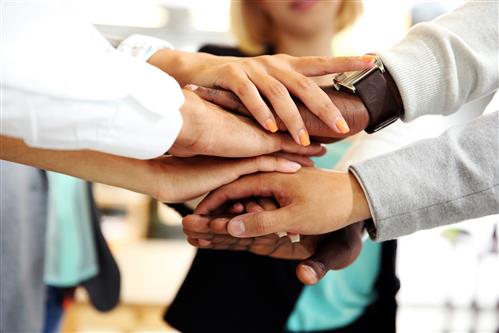 Closeup of hands stacked, men and women at work