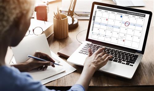 Calendar Planner on laptop screener, woman looking at screen, view over her shoulder