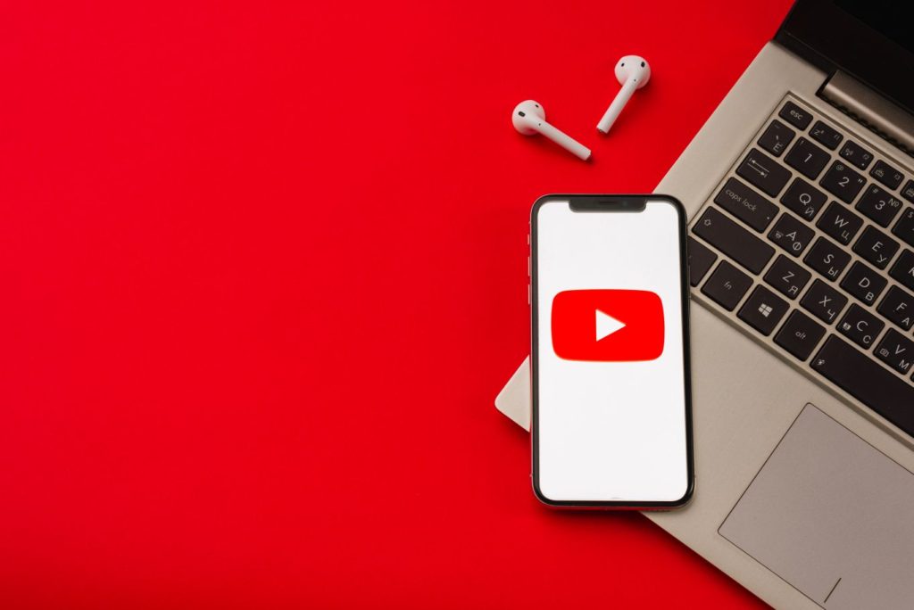 iphone, airpods and laptop on red table