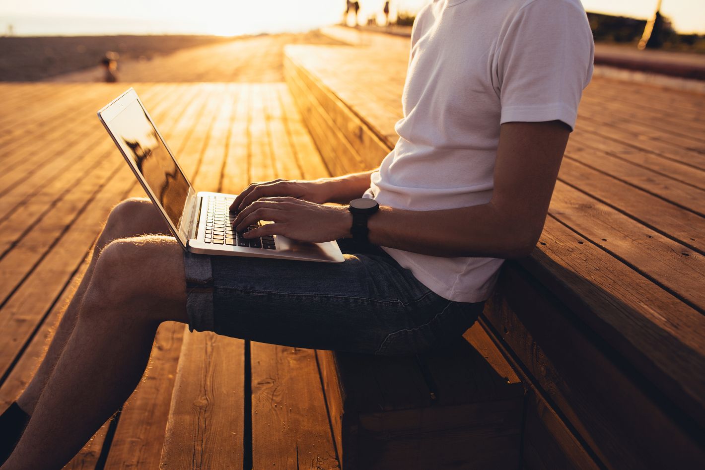 man working remotely on outdoor benches during sunset
