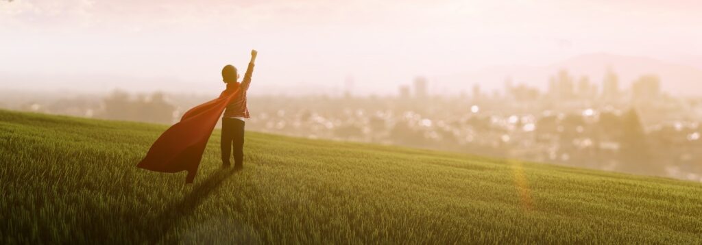 boy wearing a red cape raising fist in the air in triumph