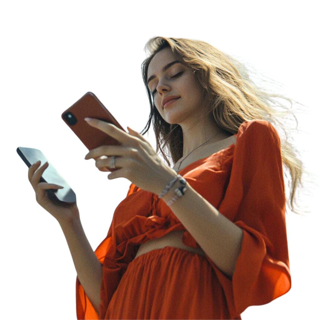 A woman wearing a red top is looking at her phone while holding another device in her other hand, perhaps managing her tasks for a marketing agency.