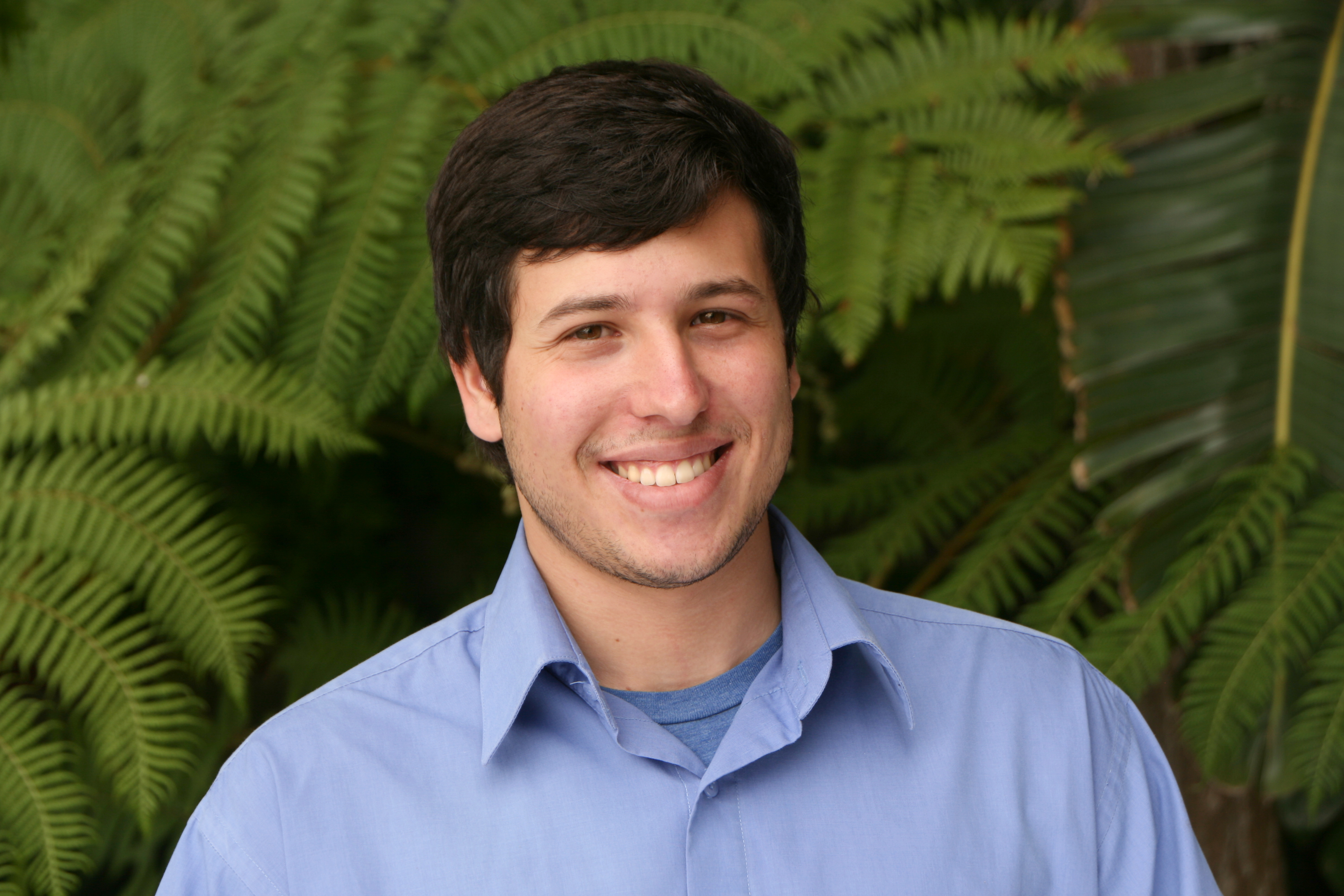 Meet The Team: A man smiling in front of a fern.